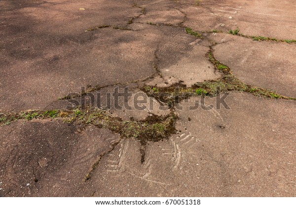 Damaged asphalt road with\
potholes. Bad road. Road repair. Patch repair of asphalt. Bad\
asphalt, dangerous, Broken automobile road, cracks, holes, potholes\
in asphalt\
