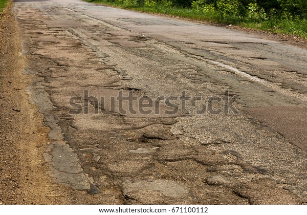 Damaged\
asphalt road with potholes. Bad road. Pitch Repair. Repair of\
asphalt repair. Bad asphalt, dangerous road, Broken automobile\
road, cracks, holes, potholes in the\
asphalt