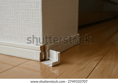 Damaged baseboard and fallen corner cap on the wall in a house