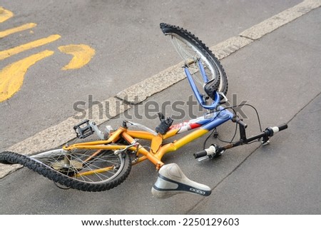 The damaged bicycle lying on the street in the city center. 