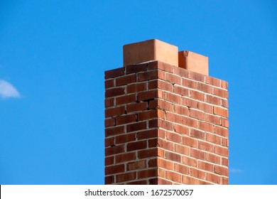 A damaged brick chimney on a blue sky