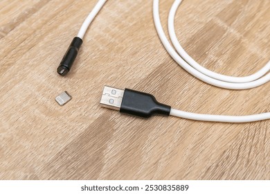 Damaged broken micro iPhone Lightning input USB port charger cable,torn mobile phone charging wire on wooden surface