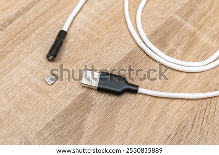 Damaged broken micro iPhone Lightning input USB port charger cable,torn mobile phone charging wire on wooden surface