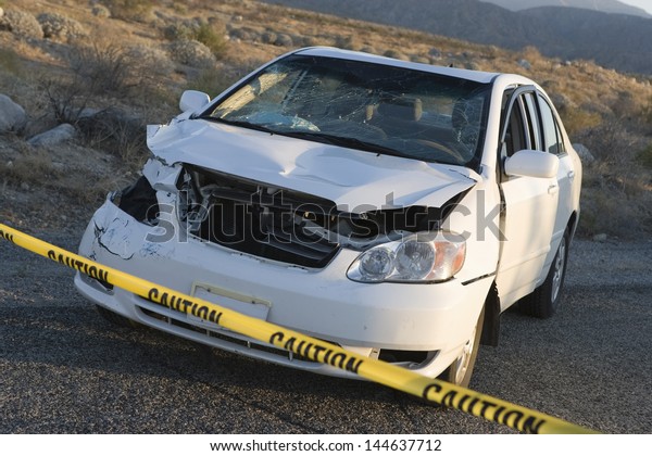 Damaged car\
behind warning tape at an accident\
scene