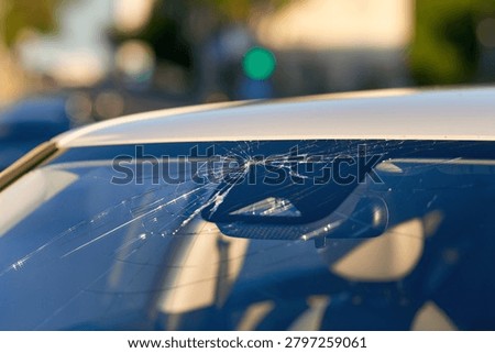Damaged car front windshield, severe crack patterns, auto glass replacement and repair needed, transportation safety and insurance claim. Cracked windshield glass with spiderweb fracture patterns