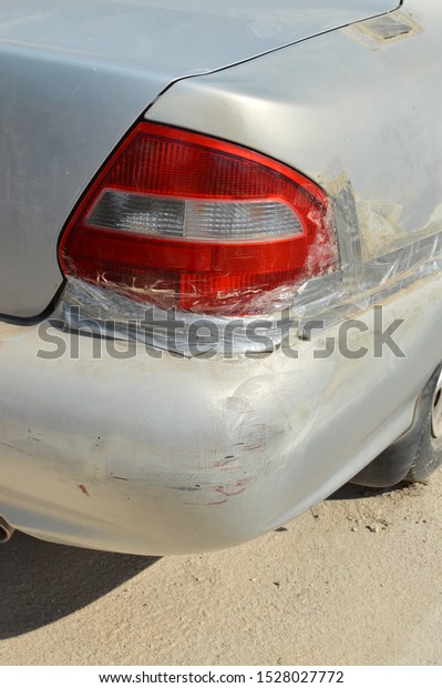 Damaged Car Tail Light Wrapped in Silver Electrical Tape\
and Clear Packing Tape and Rear Bumper with scratches and scuff\
marks light 