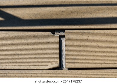 Damaged composite decking boards due to incorrect installation. Close-up of cracked and misaligned brown deck planks with visible mounting hardware.