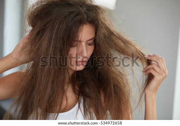 Damaged Hair. Beautiful Sad Young Woman With
Long Disheveled Hair. Closeup Portrait Of Female Model Holding
Messy Unbrushed Dry Hair In Hands. Hair Damage, Health And Beauty
Concept. High
Resolution
