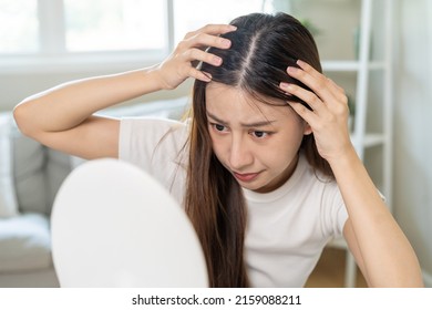 Damaged Hair, face serious asian young woman worry looking at scalp in mirror, hand in break into front hair loss, thin problem symptom at home. Health care shampoo beauty, isolated on background. - Shutterstock ID 2159088211