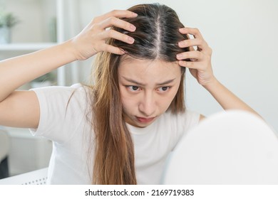 Damaged Hair, face serious asian young woman worry looking at scalp in mirror, hand in break into front hair loss, thin problem symptom at home. Health care shampoo beauty, isolated on background.