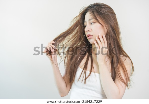 Damaged Hair, frustrated asian young woman,\
girl hand in holding splitting ends, messy unbrushed dry hair with\
face shock, long disheveled hair, health care of beauty. Portrait\
isolated on background.