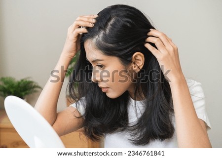 Damaged hair symptom, problem hair fall asian young woman, girl worry about balding, looking at scalp in mirror, hand in break into front hair loss, thin problem. Health care treatment for beauty. Foto stock © 