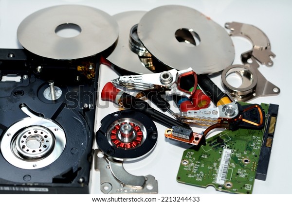 Damaged Hard disk drive components with disks, read\
write head, spindle motor, suspension, pivot, voice coil motor VCM,\
E-block, data track, platters, head arm, actuator and main logic\
board chip