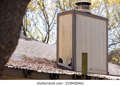 Damaged House Siding With Holes Caused By Water Infiltration Or Pests. Chimney On Top Of The Roof With Worn Out Siding And Large Holes.