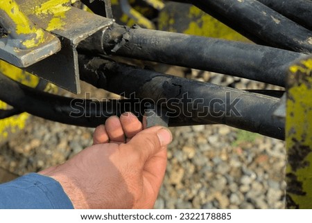 Damaged hydraulic line and man's hand pointing at the problem