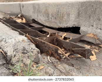A damaged and mangled metal storm drain grate on a street in San Marcos.