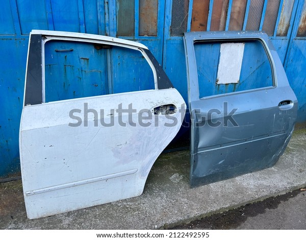 Damaged old car\
doors leaning on wall at entrance of dent repair technician service\
or junk yard. repair and remove dents on body and prepare surface\
for spray painting in car\
service