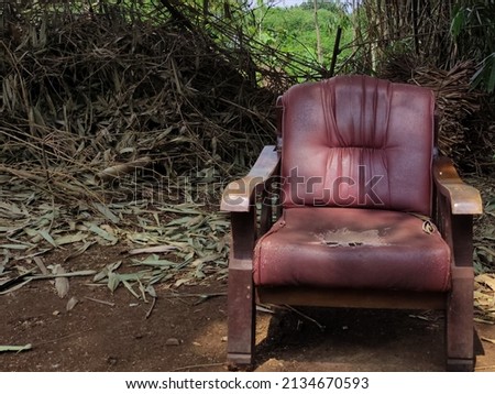 Damaged old wooden chair. Broken chair abandoned in bamboo forest