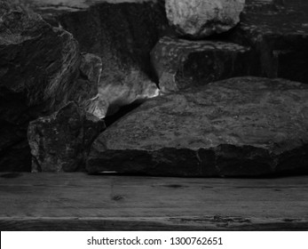 A Damaged Pine Shelf For A Product Display, Showing The Soft Grain Of The Wood With A Blurred Backlit Rock And Stone Background.