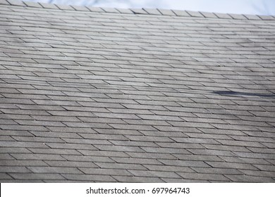 Damaged shingles on a roof after a storm