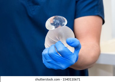 Damaged torn gummy bear breast implant in surgeon's hands. Demonstration of the reliability of the breast implant, it is damaged, but the gel remains inside it. Risks of breast implant surgery