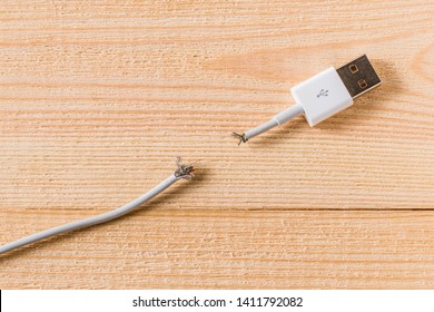 Damaged USB Charger Cable On Wooden Surface