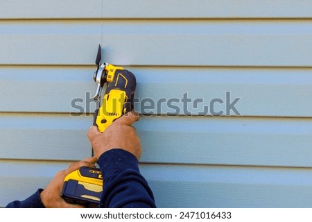 Damaged vinyl siding is removed using multi tool during reconstruction of house