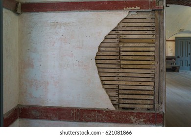 Damaged Wall With Broken Drywall And Exposed Slats And Timber Underneath