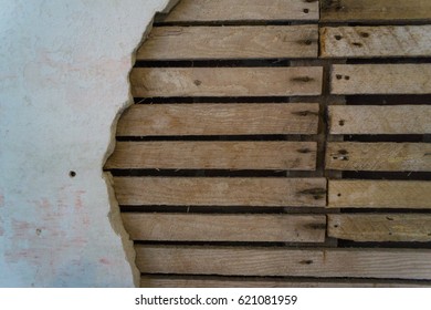 Damaged Wall With Broken Drywall And Exposed Slats And Timber Underneath