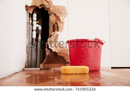 Damaged wall, exposed burst water pipes, sponge and bucket