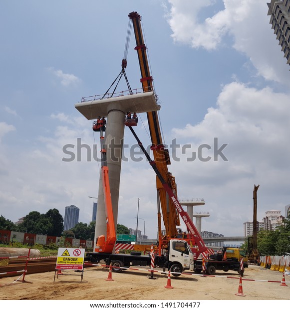 Damansara,\
Malaysia. August 29 2019. Mobile crane is lifting heavy load with\
assisting from signal men on the sky\
lift.