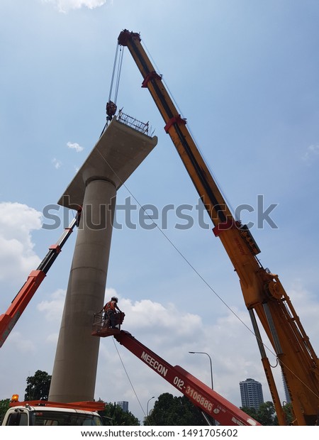 Damansara,\
Malaysia. August 29 2019. Mobile crane is lifting heavy load with\
assisting from signal men on the sky\
lift.