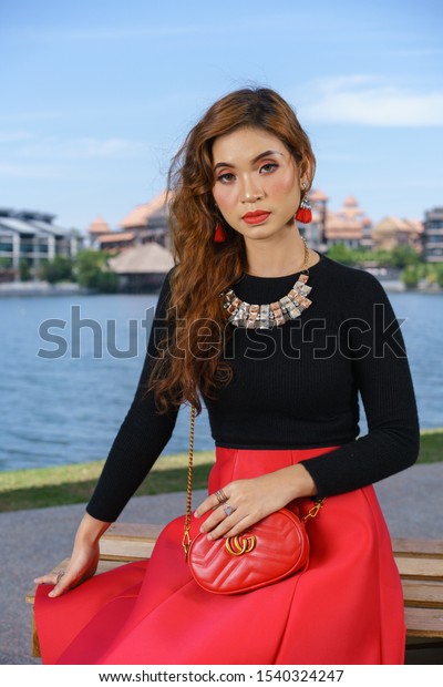 Damansara,\
Malaysia - Oct 2019 : Attractive asian woman with long beautiful\
hair wearing black long sleeve shirt with red skirts posing in\
urban environments. Lifestyle\
concept.