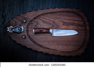 Damascus kitchen steel Knives on Wooden kitchen cutting Board. Kitchen Utensils background with Santoku Japanese knife damascus steel blade knife. Japanese knife made of Damascus steel