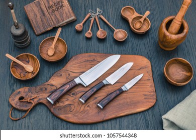 Damascus kitchen steel Knives, Wooden kitchen cutting Board, wooden kitchen measuring spoons,   Recipe Book. Kitchen Utensils background with Santoku damascus steel blade knife. Santoku knife