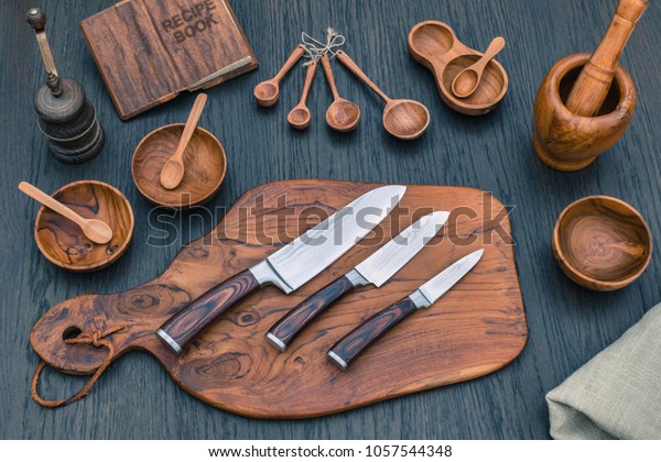 Damascus kitchen steel Knives, Wooden kitchen cutting Board, wooden kitchen measuring spoons,   Recipe Book. Kitchen Utensils background with Santoku damascus steel blade knife