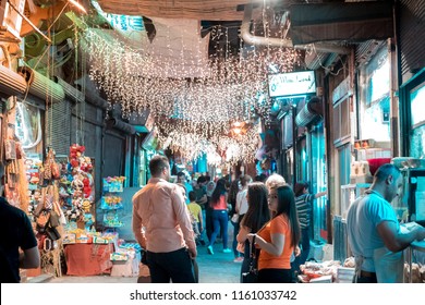 Damascus / Syria - 25/07/2018: Night Photo Of A Narrow Alley In The Old City Near The Umayyad Mosque In Bab Touma, Al Qaymariyya And Bab Sharqi With People Walking Under The Street Lights. 