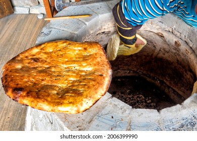 Damirchi, Azerbaijan - 09 08 2019: Woman cooking tandir bread in a traditional tandoor