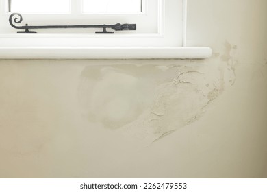 Damp patch under a window of a solid brick wall due to rain penetrating brickwork of old UK house