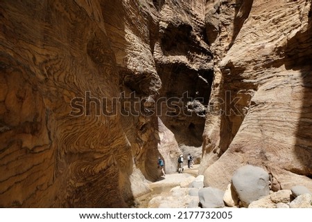 Dana Biosphere Reserve in Jordan. Amazing rocks in Wadi Ghuweir Canyon. Silhouette of hiking people on trail. 