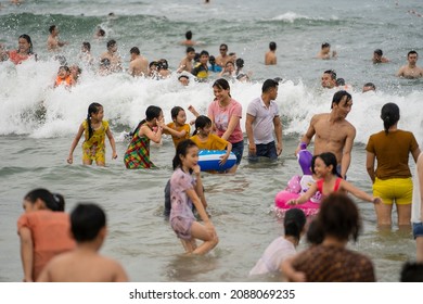 Danang, Vietnam - june 14, 2020 : Vietnamese families relax on the beach and swim in the sea in the evening after work on the city Danang, Vietnam. Local people relax on the beach