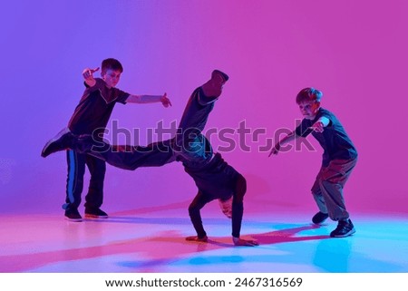 Dance battles. Dancer performing impressive headstand, breakdance moves mixed neon light against vibrant gradient background. Concept of sport and hobby, music, fashion and art, movement. Ad