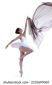 Dance Concepts. Professional Japanese Female Ballet Dancer Posing in White Tutu With Flying Black Cloth In Hands Against White Background. Vertical Shot