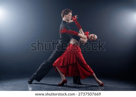Dance couple performing a dramatic partner pose with controlled movement in a studio setting. Ideal for advertising banners, websites, and promotional visuals focused on emotion and motion.