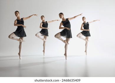 Dance in harmony. Beautiful teen girls, ballerinas in black leotards and pointe in motion, dancing against gray studio background. Concept of ballet, art, dance studio, classical style, youth - Powered by Shutterstock