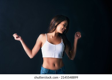 Dance Like You Have No Care In The World. Studio Shot Of An Attractive Young Woman Dancing Against A Dark Background.