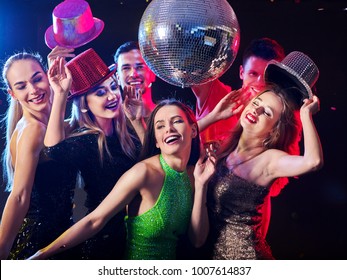 Dance Party With Group People Dancing. Women And Men Have Fun In Night Club. Happy Girl On Foreground And Disco Ball On Background. Guys Took Off Their Hats. Rest After Hard Day At Work.