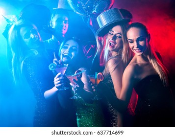 Dance Party With Group People Dancing . Women And Men Have Fun And Drinking Martini Cocktail In Night Club. Girl On Foreground And Disco Ball Color Illumination Background. Rest After Hard Day's Work.