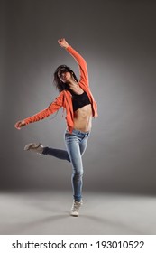 Dance passion. Female is dancing on one leg and arms outstretched. Full length studio shot on gray background.