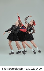 Dance show. Professional women's Irish dance ensemble in concert costumes and Ghillies Hard Shoes pose together in a row. Full-length studio portrait on a grey background. - Shutterstock ID 2310291409